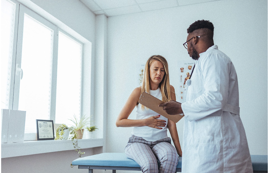 A woman in pain due to ectopic pregnancy, in consultation with a doctor taking notes