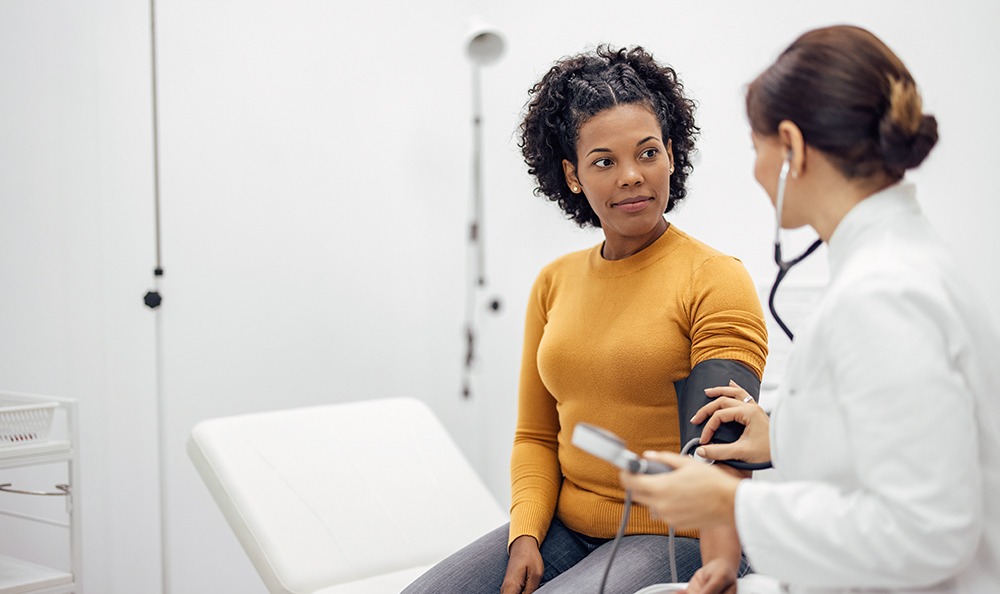 Médecin mesurant la tension artérielle d'une femme souriante.