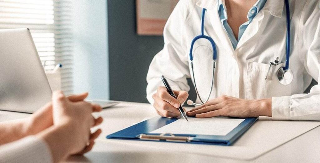 Une médecin rédigeant une ordonnance ou une référence médicale pour un patient lors d'un examen de routine.