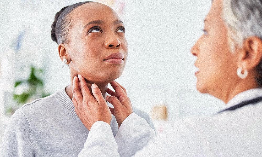A female doctor examines the neck of a female patient in a doctors office during a thyroid check.&nbsp;