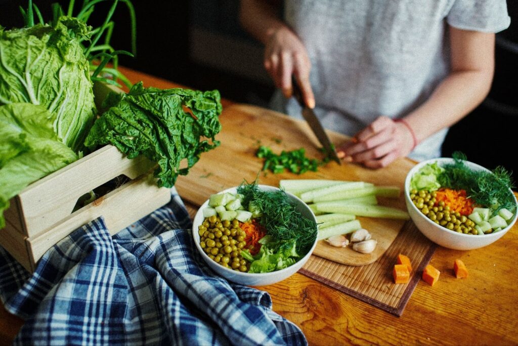Divers aliments sains sur un plan de travail de cuisine pendant que quelqu'un prépare une salade.